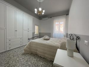 een witte slaapkamer met 2 bedden en een kroonluchter bij Casa Nonna Amalia in Terzigno