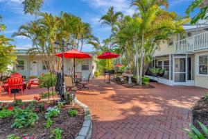 a patio with palm trees and red umbrellas at Sea Gem One bed one bath charmer steps to beach in Bradenton Beach