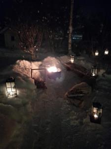 eine Feuerstelle mit Lichtern im Schnee in der Nacht in der Unterkunft Lapland winter cottage in Rovaniemi