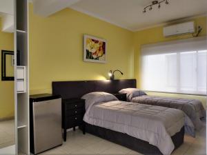 Duas camas num quarto com paredes amarelas em Posada Relmú em Neuquén