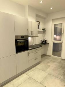 cocina blanca con armarios blancos y ventana en Comfort Apartment, en Lörrach