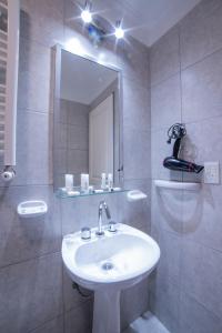 a bathroom with a white sink and a mirror at Posada Relmú in Neuquén