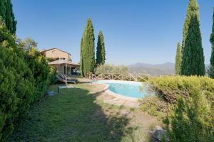 uma piscina num quintal com árvores e um guarda-sol em La Casa della Luna - Villa con piscina em Dolceacqua