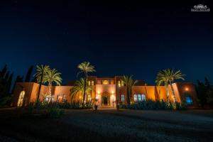 a home at night with palm trees in front at Palais Hassoun Marrakech in Oulad Snaguia