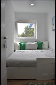 a bed with green and white pillows sitting under a window at Apartamentos Playa de Mogro in Miengo