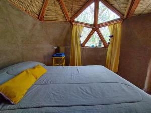 Cama en habitación con ventana grande en Casa Arbol Domos en Cafayate