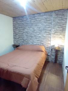 a bed in a room with a brick wall at Macrigaluma Sol con seña in Barra del Chuy