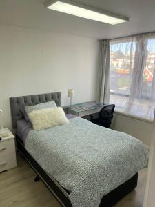 a bedroom with a bed and a desk and a window at Departamento central viña del mar in Viña del Mar