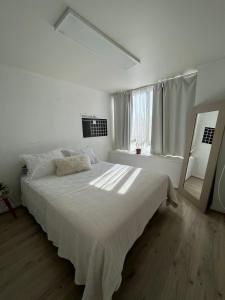a white bedroom with a large bed and a mirror at Departamento central viña del mar in Viña del Mar