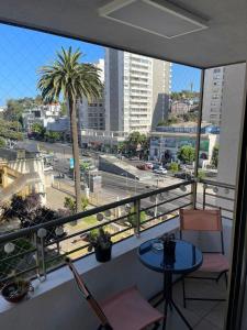 a balcony with a table and chairs and a palm tree at Departamento central viña del mar in Viña del Mar