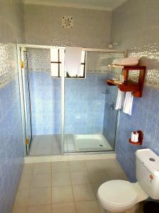 uma casa de banho com um chuveiro e um WC. em The Farmhouse Inn em Nanyuki