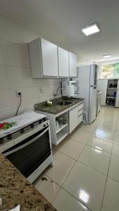 a kitchen with white cabinets and a stove and refrigerator at Apt. em Praia do Sul de Ilhéus in Ilhéus