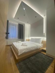 a white bedroom with a large bed with a window at Apartments Natalija - Zlatni Javor in Jahorina