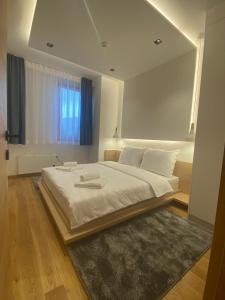 a bedroom with a large white bed with a large window at Apartments Natalija - Zlatni Javor in Jahorina