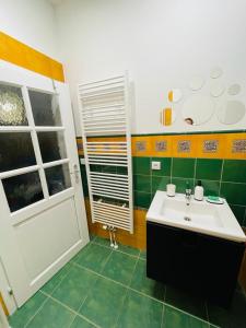 zieloną i białą łazienkę z umywalką i oknem w obiekcie Apartmán U Splavu w mieście Teplice nad Metují