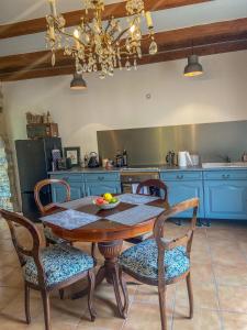 une cuisine avec une table en bois et des chaises ainsi qu'une salle à manger dans l'établissement Le Mas de Roussa, à Meyrannes
