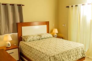 a bedroom with a bed and two lamps and a window at Villa Eliam in San Felipe de Puerto Plata