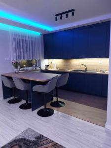 a kitchen with blue cabinets and a table and chairs at Bee Happy Apartament Wrzesnia ll in Września