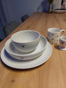 a table with plates and cups on a wooden table at Bee Happy Apartament Wrzesnia ll in Września