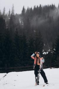 una mujer está parada en la nieve sosteniendo esquís en Nikol Guest House, en Bukovel