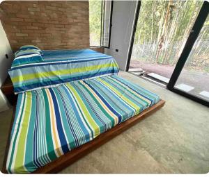 uma cama com lençóis listrados num quarto com uma janela em Casa campestre Lago Calima em Calima