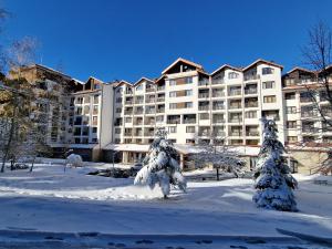 a large apartment building in the snow with trees at Borovets Gardens Apartments TMF in Borovets