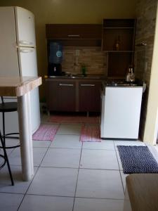 uma cozinha com piso em azulejo branco e um frigorífico em AP praia Itaguaçu São Chico em São Francisco do Sul