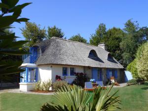 a thatch roof house with blue windows and a yard at Ty Papy in Bénodet