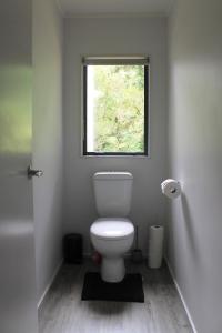a bathroom with a toilet and a window at Orchid Lane Bay of Island in Haruru