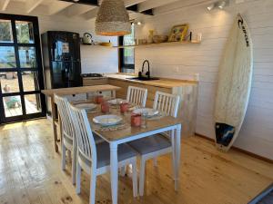 une cuisine avec une table et des chaises ainsi qu'une planche de surf dans l'établissement Casas Antubureo, à Cáhuil