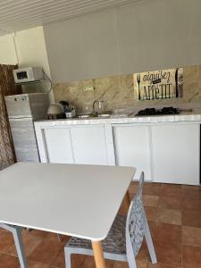 a kitchen with white cabinets and a white table at Casa DeLyZy in Matoury