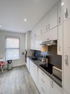 uma cozinha com armários brancos e uma bancada em Beautiful 1 Bedroom Flat Close to City Centre em Londres