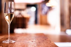 una copa de vino blanco en una mesa de madera en Hotel Bergidyll - Riders Haven en Andermatt