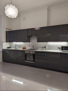 a large kitchen with black cabinets and a sink at Victorian Apartment on the Famous Essex Rd in Islington in London