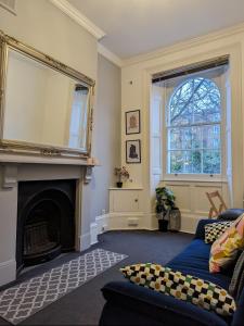 a living room with a fireplace and a mirror at Victorian Apartment on the Famous Essex Rd in Islington in London