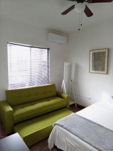 Sofá verde en un dormitorio con cama en Confortable Loft MN 960 E Centro Mty cerca de todo, en Monterrey