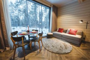a living room with a table and a couch and a window at Invisible Forest Lodge in Rovaniemi