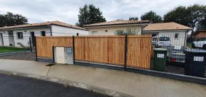 a wooden fence in front of a house at Charmant logement neuf in Hourtin