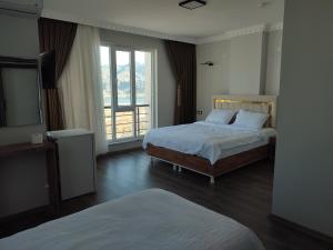 a bedroom with two beds and a large window at Hasankeyf Hasbahce Mervani Hotel in Hasankeyif
