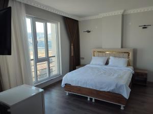 a bedroom with a bed and a large window at Hasankeyf Hasbahce Mervani Hotel in Hasankeyif