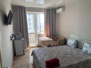 um pequeno quarto com uma cama, uma mesa e uma janela em ObolonSky em Kiev