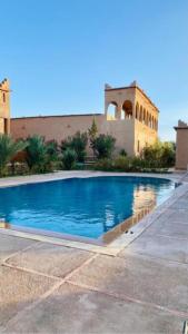 a swimming pool in front of a building at Auberge Famille Benmoro in Skoura