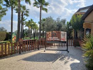 una señal frente a una valla con palmeras en MERSINERA Paradise Garden 2, en Lárnaca