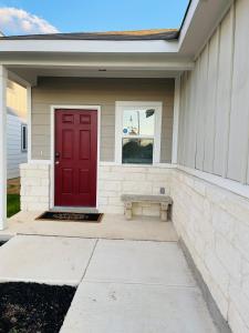 a red door on a house with a bench at New House family friendly near Six Flags Sea World in Helotes