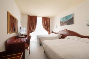 ノヴェンタ・ディ・ピアーヴェにあるノヴェンタ ホテルのベッド2台とテレビが備わるホテルルームです。