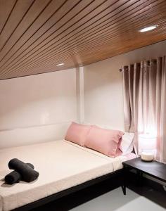 uma cama com almofadas cor-de-rosa num quarto com uma janela em Cozy Loft Near the Airport & Beach-Unit I em Puerto Princesa