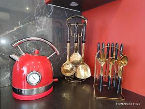 a red tea kettle and utensils on a counter at Your hidden charm by Paris in Le Kremlin-Bicêtre