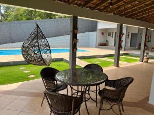 a glass table with chairs and a umbrella on a patio at Chácara em Alpes de Mairiporã in Mairiporã