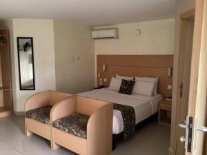 une chambre d'hôtel avec un lit et une chaise dans l'établissement Adis Hotels Ibadan, à Ibadan