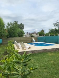 a swimming pool with white chairs in a yard at Cabañas Los Acacios Complejo Lobos in Lobos